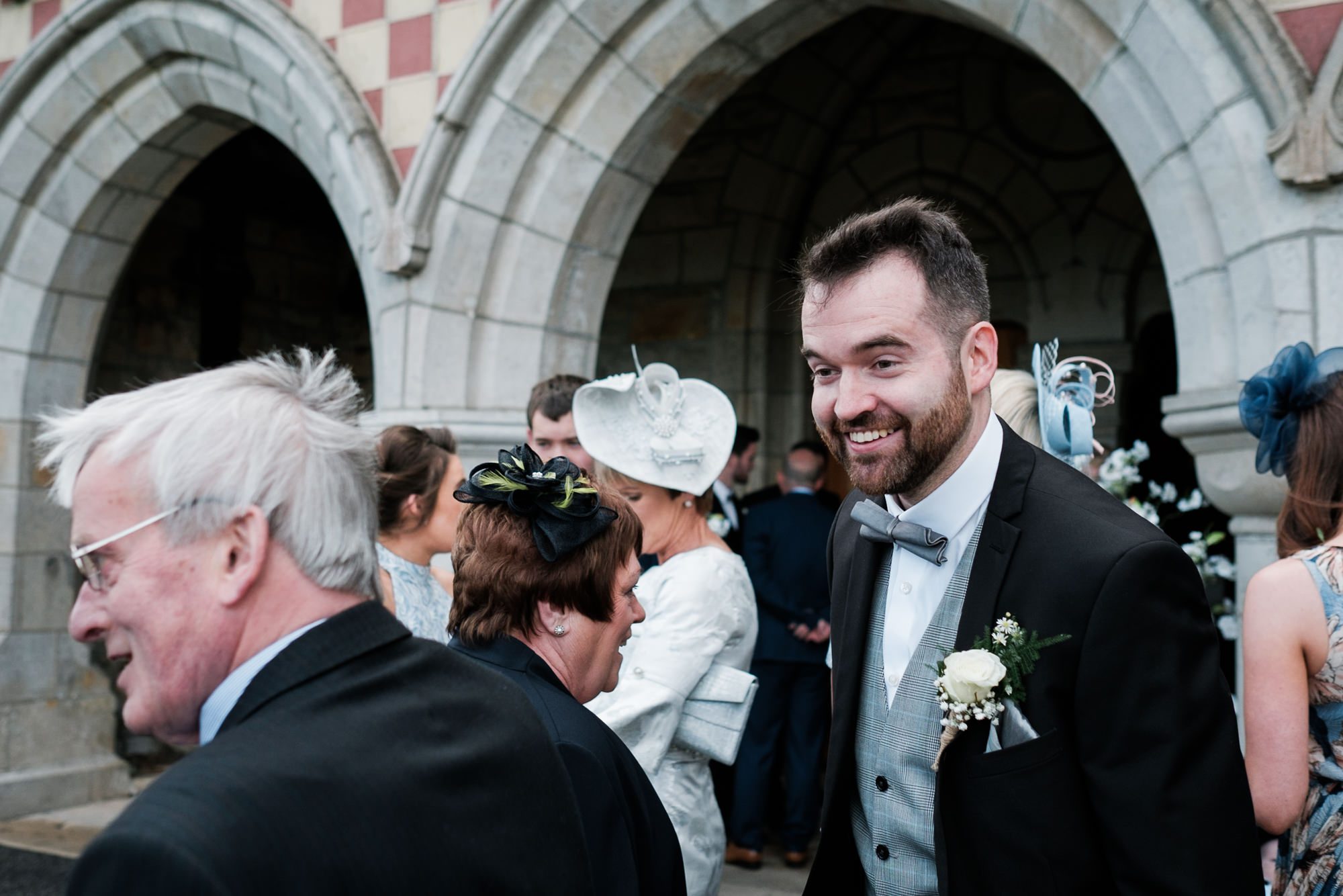 groom welcoming guests at church