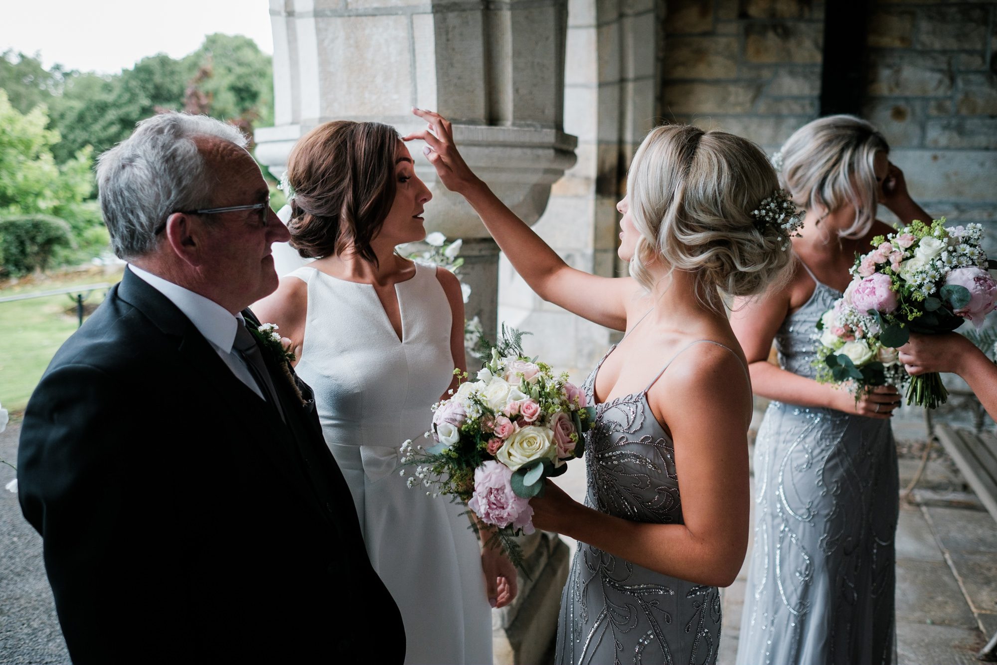 bridesmaid adjusting brides hair