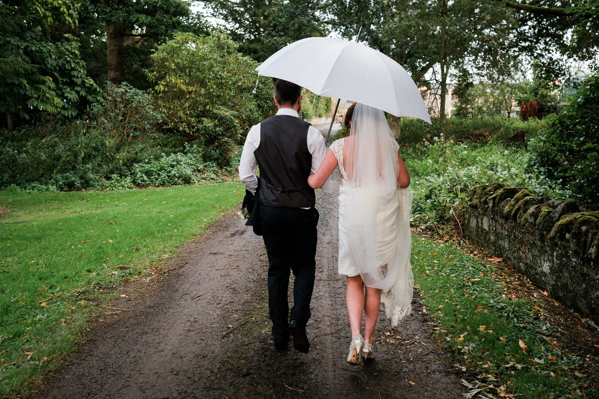 bride and groom retreating under umbrella