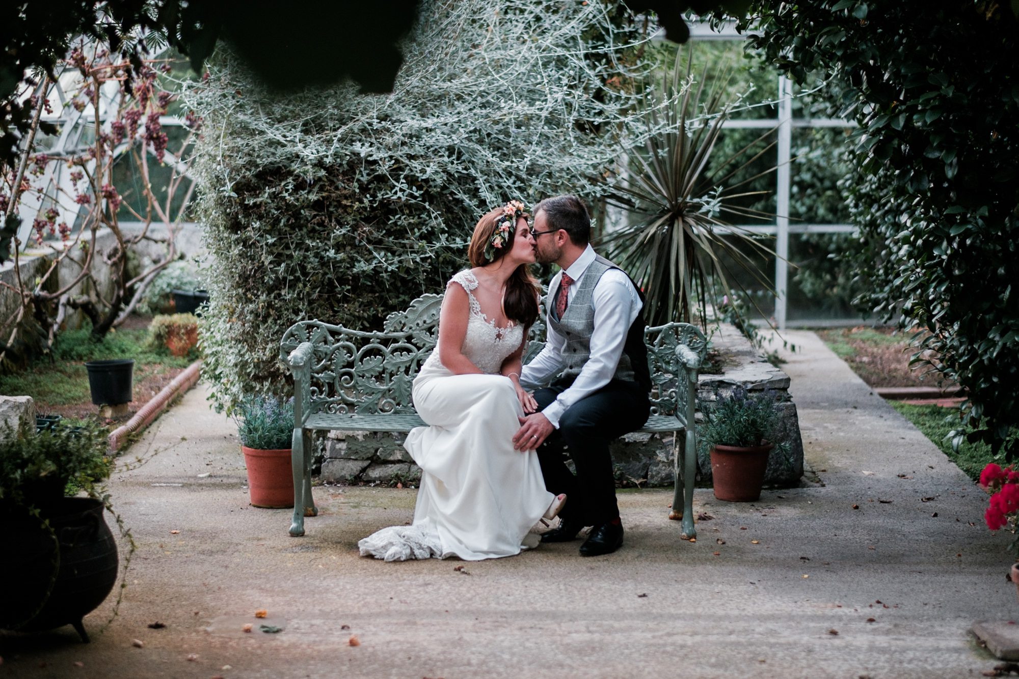 bride and groom kissing in greenhouse
