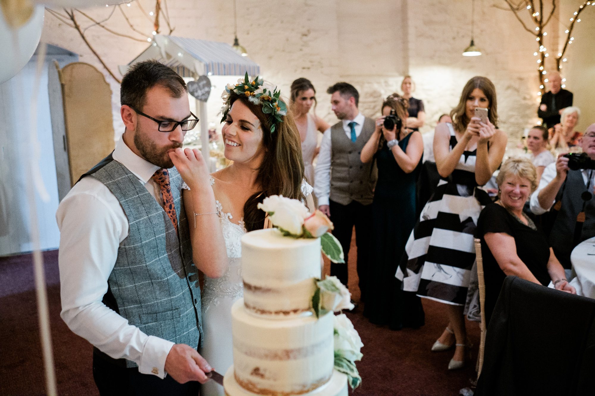 bride and groom tucking into cake after cutting