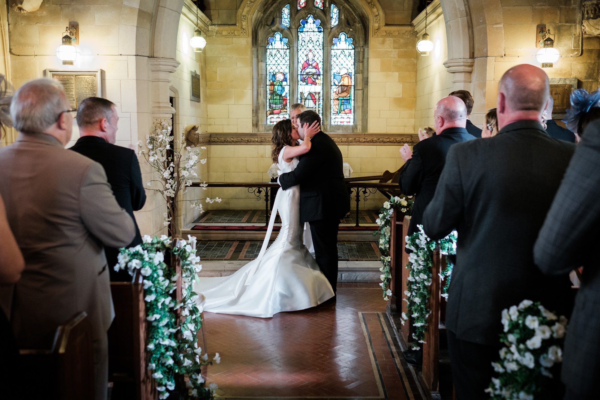 bride and groom kiss at top of aisle